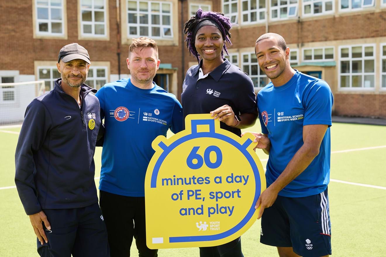 A group of people holding a 60 minutes a day of PE sign and smiling at camera