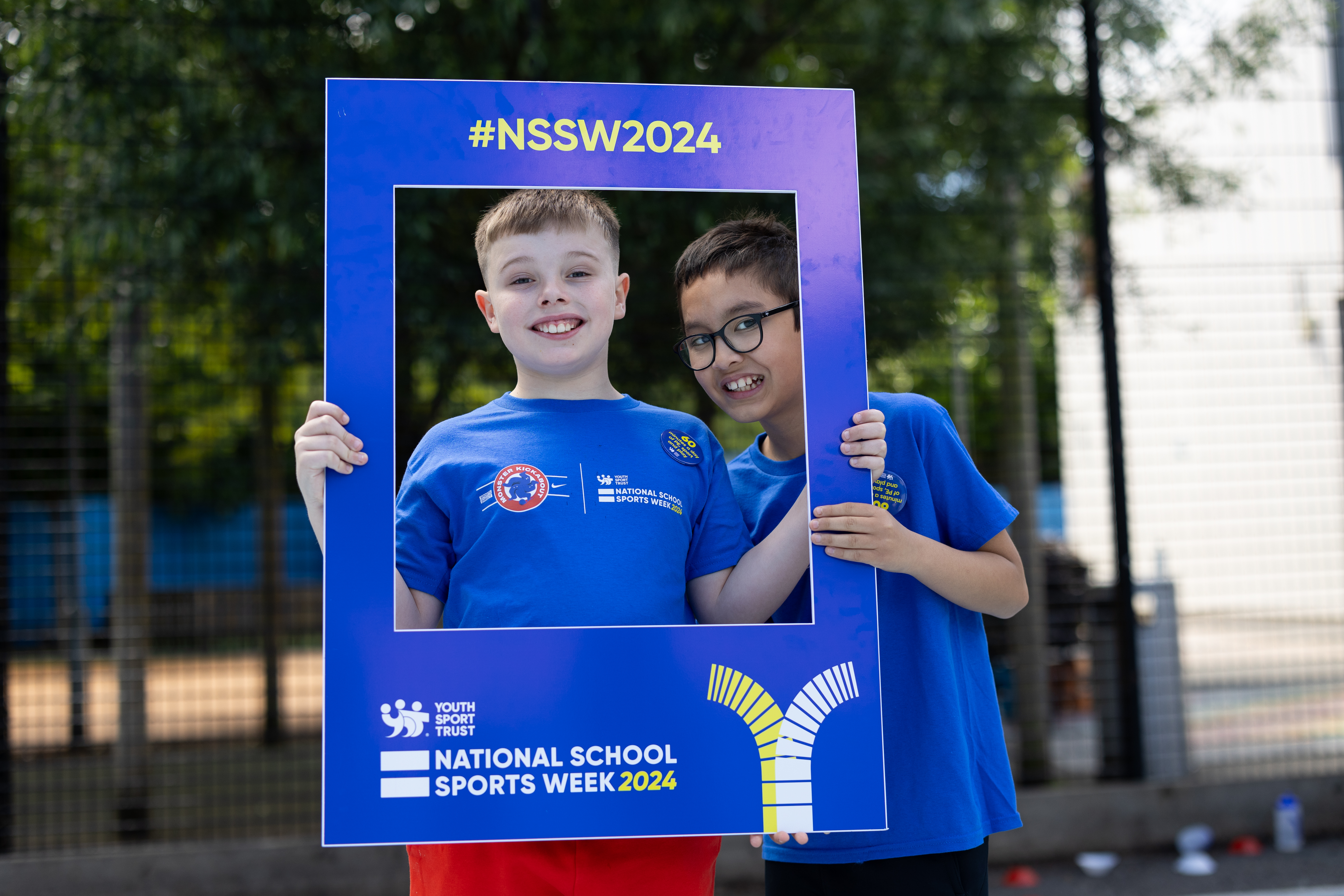 Two boys smiling through a National School Sports Week posing frame.